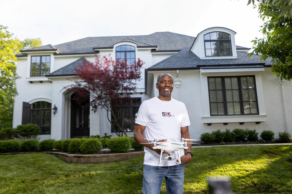 Small business owner Reggie Hines smiles in front of a client's home